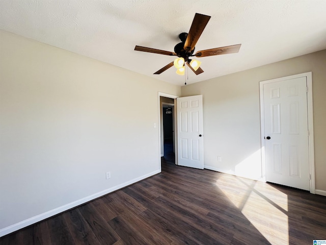 unfurnished bedroom featuring dark wood-type flooring, ceiling fan, and baseboards