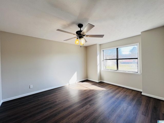 empty room featuring ceiling fan, a textured ceiling, baseboards, and dark wood-style flooring