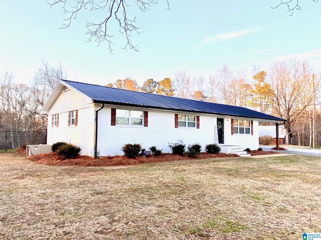 ranch-style home with brick siding, metal roof, and a front yard