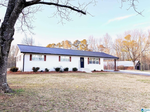 ranch-style house with a carport, brick siding, metal roof, and a front lawn