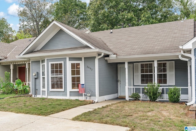 view of front of house with a porch, a front yard, and roof with shingles