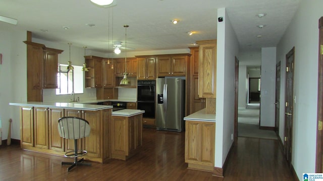 kitchen featuring brown cabinetry, decorative light fixtures, a peninsula, light countertops, and stainless steel refrigerator with ice dispenser