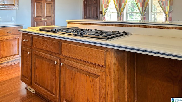 kitchen with light countertops, light wood-style floors, brown cabinetry, and stainless steel gas stovetop