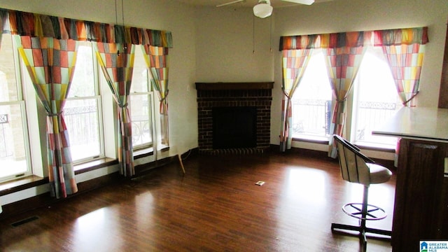 unfurnished living room featuring dark wood-style floors, visible vents, a fireplace, and baseboards