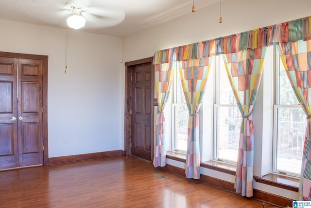 interior space featuring baseboards, visible vents, a ceiling fan, and wood finished floors