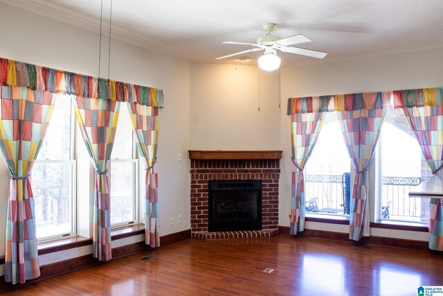 unfurnished living room with a ceiling fan, a wealth of natural light, dark wood-style flooring, and a fireplace