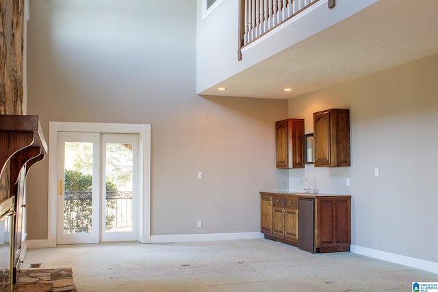 unfurnished living room featuring light carpet, baseboards, a towering ceiling, a sink, and recessed lighting