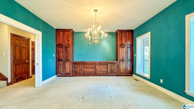 unfurnished dining area featuring light colored carpet, visible vents, baseboards, and an inviting chandelier