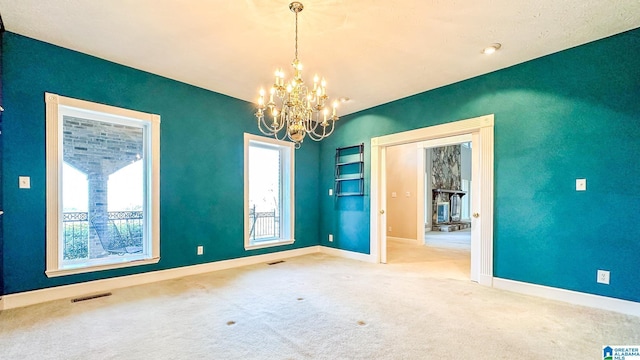 empty room with carpet, visible vents, a chandelier, and baseboards