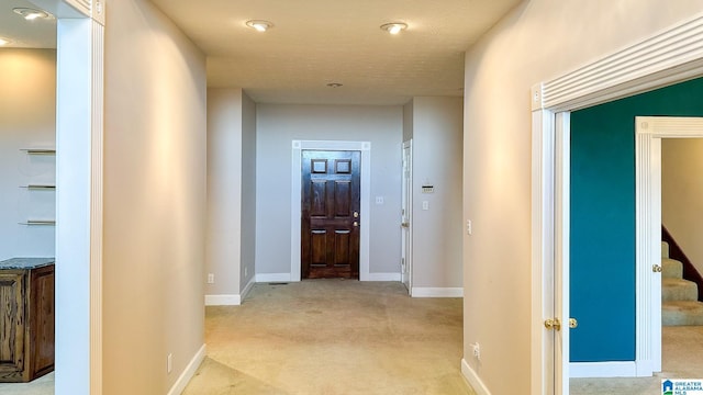 corridor with light colored carpet, baseboards, and stairs