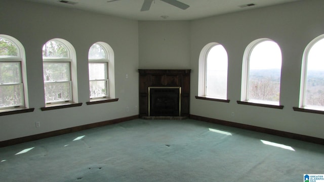 unfurnished living room featuring light colored carpet, visible vents, a ceiling fan, a high end fireplace, and baseboards