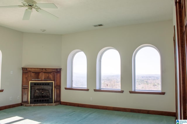 unfurnished living room with a fireplace with raised hearth, ceiling fan, light colored carpet, visible vents, and baseboards