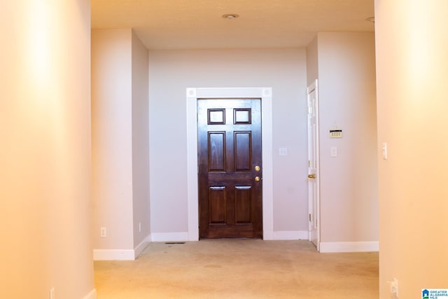 entrance foyer featuring light carpet and baseboards