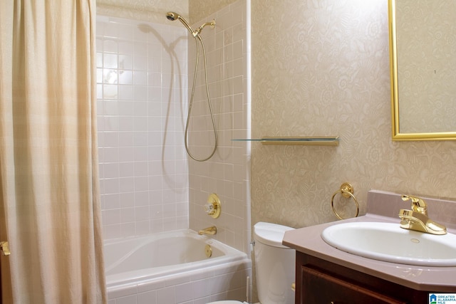 full bath with vanity, tiled shower / bath, toilet, and wallpapered walls