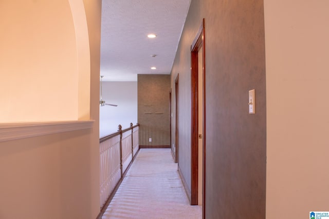 corridor featuring recessed lighting, light colored carpet, a textured ceiling, and baseboards