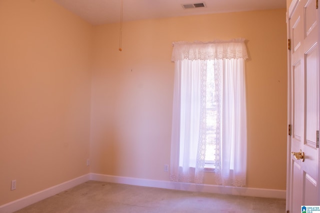 spare room featuring light carpet, visible vents, and baseboards