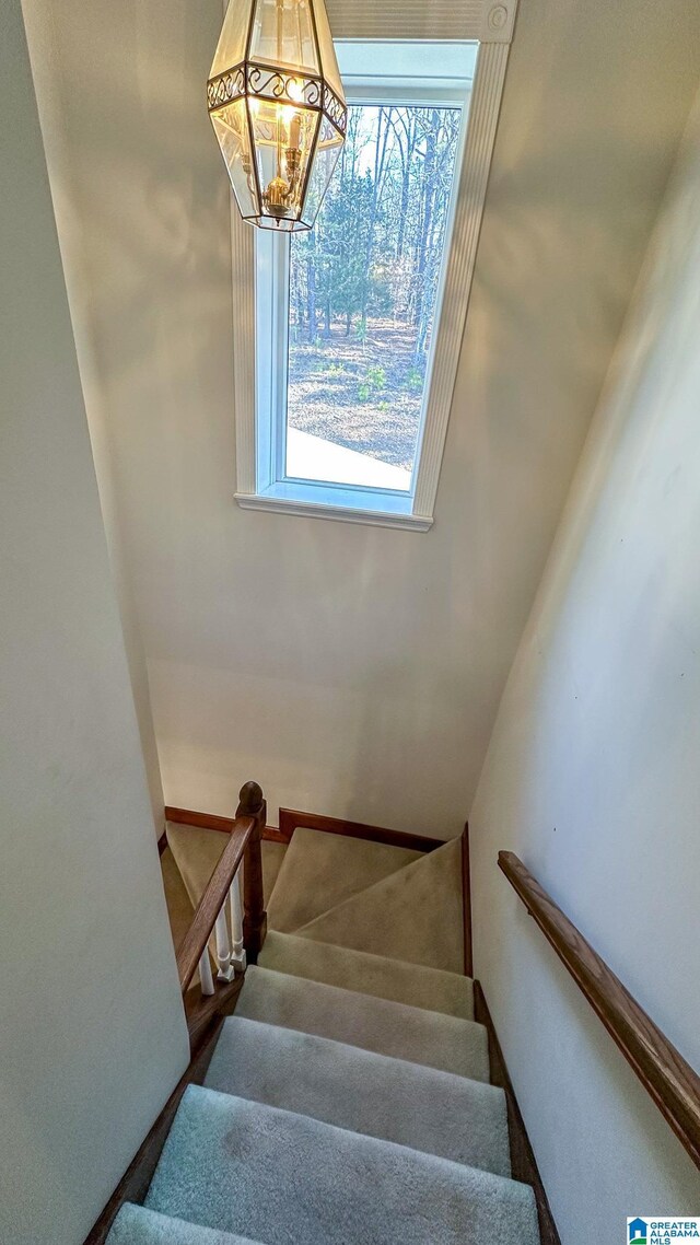 staircase with a notable chandelier