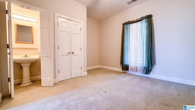 unfurnished bedroom with baseboards, a closet, visible vents, and light colored carpet