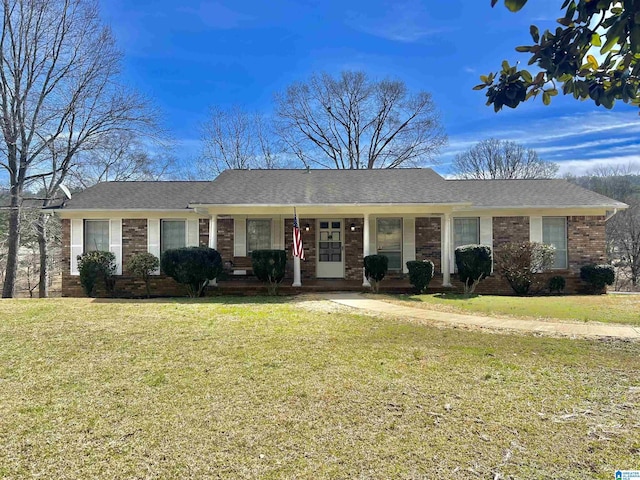 single story home with a front yard, covered porch, brick siding, and a shingled roof