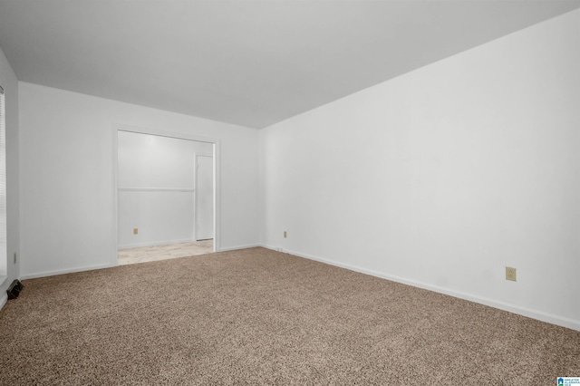 unfurnished room featuring light carpet and baseboards