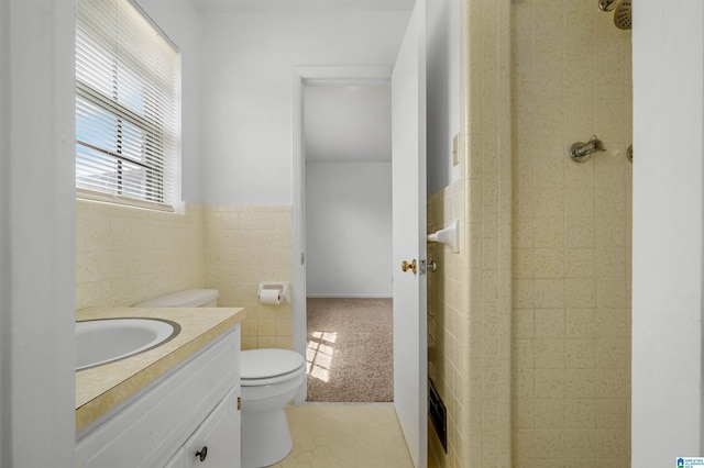 bathroom featuring toilet, vanity, tile walls, wainscoting, and walk in shower