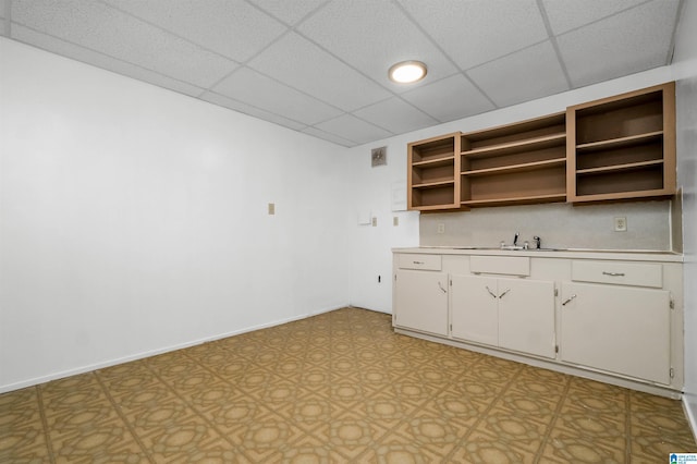 interior space with baseboards, light countertops, light floors, white cabinetry, and open shelves