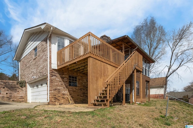 rear view of house featuring brick siding, stairway, a deck, a garage, and driveway