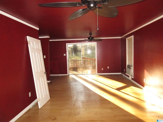 spare room with baseboards, crown molding, and wood finished floors