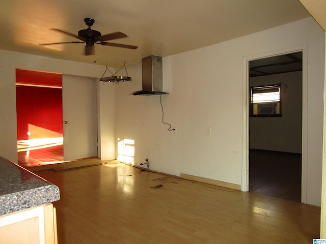 unfurnished living room featuring ceiling fan, cooling unit, and wood finished floors