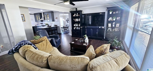 living area with bar area, ornamental molding, dark wood finished floors, and a ceiling fan