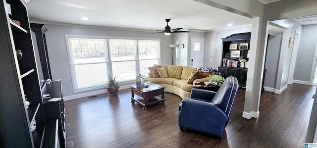 living area with dark wood-style floors, crown molding, visible vents, a ceiling fan, and baseboards