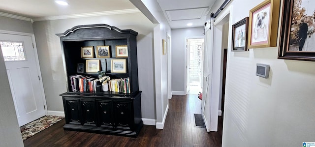 corridor featuring crown molding, dark wood finished floors, baseboards, and a barn door