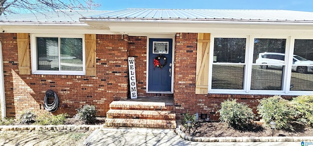 view of exterior entry with metal roof and brick siding