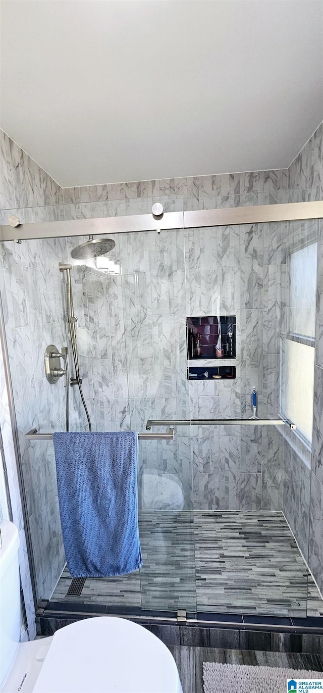 bathroom with a shower stall and toilet