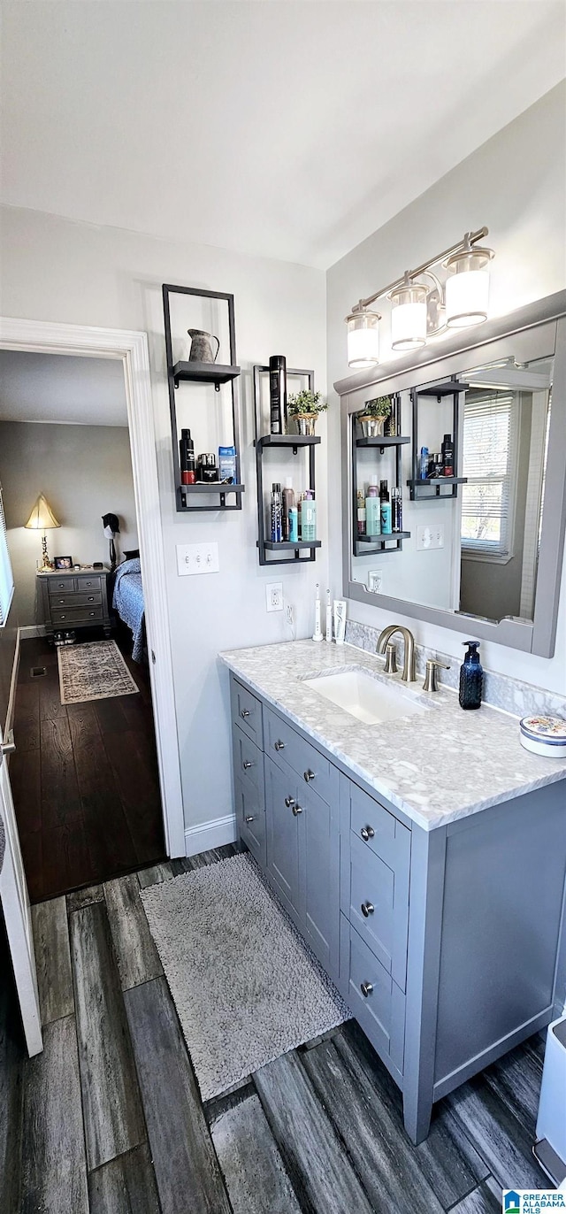 bathroom featuring baseboards, wood finished floors, vanity, and connected bathroom