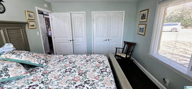 bedroom featuring a barn door, baseboards, and two closets