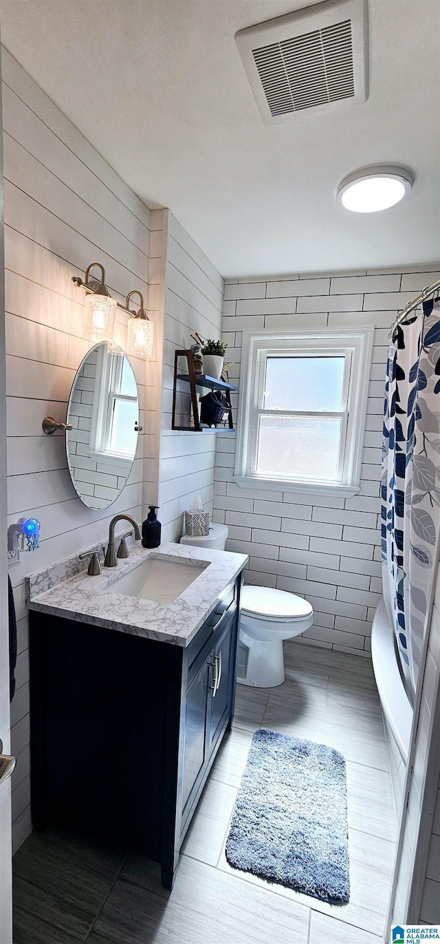 bathroom with wooden walls, visible vents, toilet, a shower with curtain, and vanity