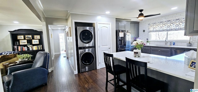 kitchen featuring stacked washer and dryer, gray cabinets, light countertops, black fridge with ice dispenser, and a sink