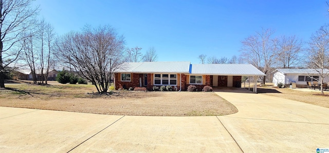 ranch-style house with metal roof, an attached carport, brick siding, concrete driveway, and a front yard