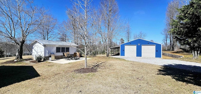 view of yard featuring an outbuilding, a detached garage, driveway, and a patio