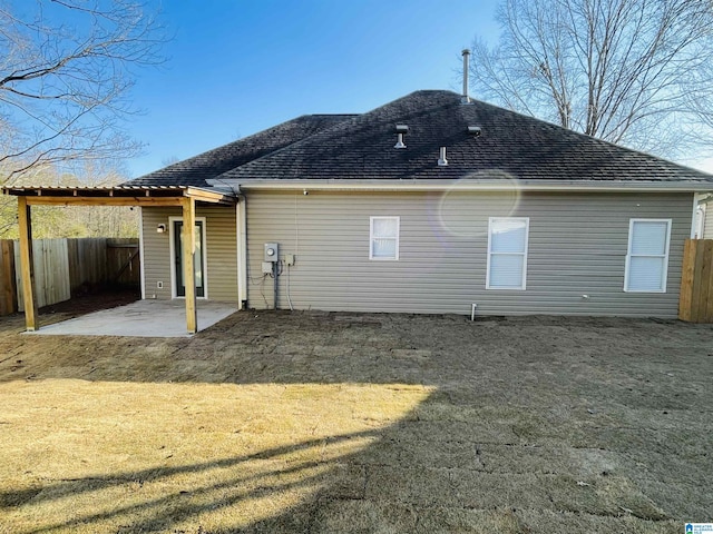 back of house with a shingled roof, a patio area, a yard, and fence