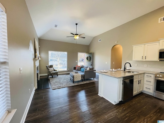 kitchen featuring appliances with stainless steel finishes, open floor plan, white cabinets, a sink, and a peninsula