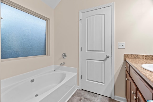 bathroom with a bath, baseboards, vanity, and tile patterned floors