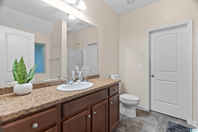 bathroom with baseboards, visible vents, toilet, a shower with shower door, and vanity