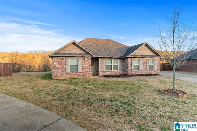 view of front of home with brick siding, a front yard, and fence