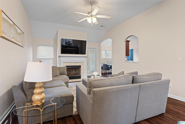 living area with dark wood-style floors, a premium fireplace, a ceiling fan, and baseboards