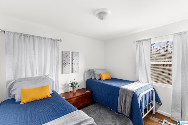 bedroom with dark wood-style floors, visible vents, and baseboards