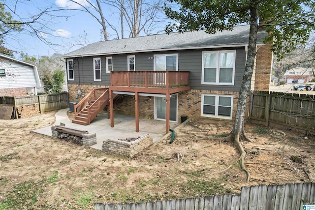 rear view of house featuring brick siding, a patio area, a fenced backyard, a wooden deck, and stairs