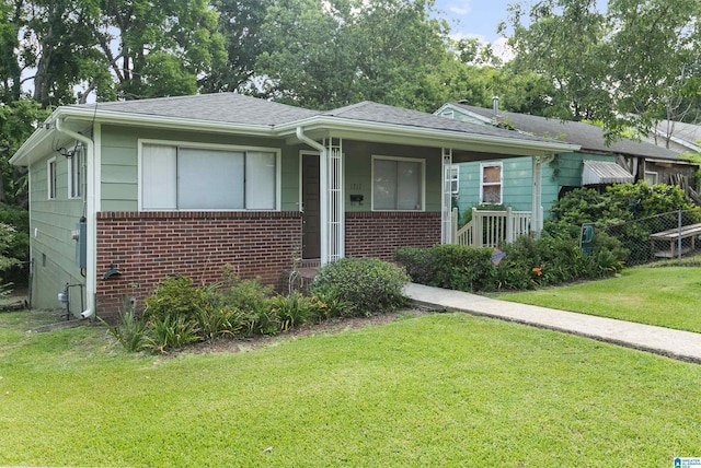 bungalow-style home with a shingled roof, a front lawn, and brick siding