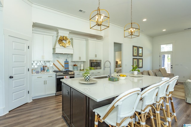 kitchen featuring visible vents, appliances with stainless steel finishes, ornamental molding, premium range hood, and a sink